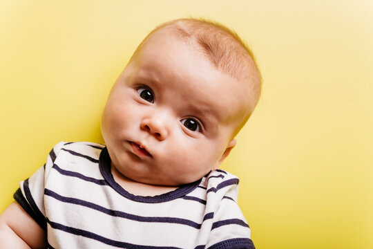Portrait of sceptical baby girl in front of yellow background