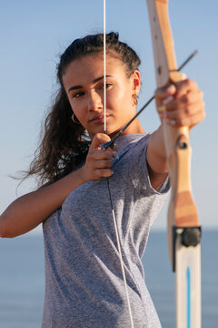 Young woman practicing archery with bow and arrow