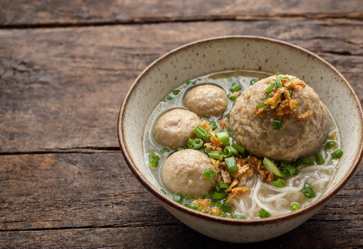 Indonesian traditional meatball soup bakso served with noodles, boiled egg, fried onion, and savory broth top view flat lay
