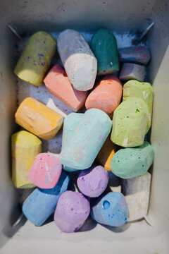 View from above of multicolored pastel sidewalk chalk in gray container