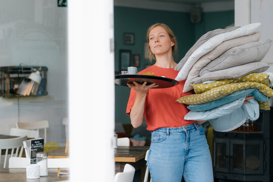 Young woman holding tray and cushions in a cafe