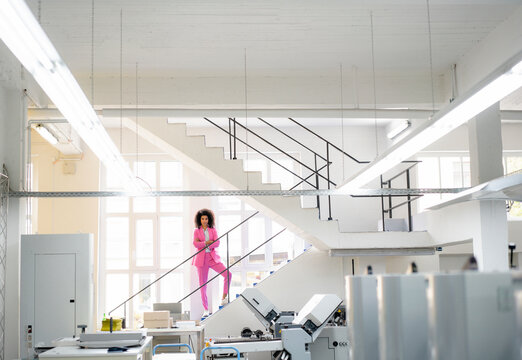 Afro businesswoman with arms crossed standing on steps in industry