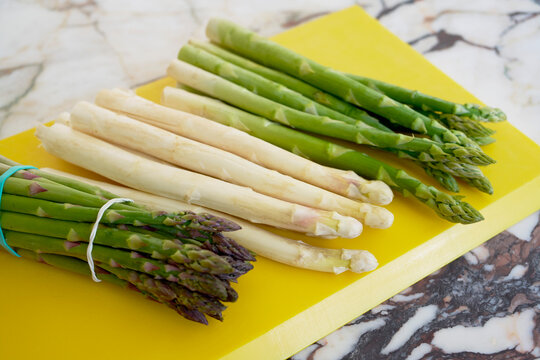 Still life of white and green asparagus spears on yellow cutting board
