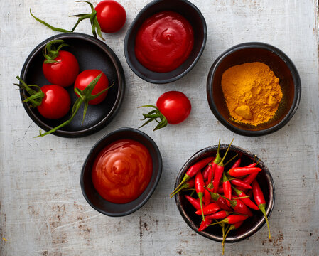 Tomatoes, red chili, curry powder, chili ketchup, curcuma and tomato ketchup in bowls