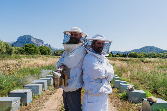 Beekeeper team stands back to back at an outdoor apiary