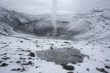 Snow-covered volcanic crater with steam rising from a crack. © Steve