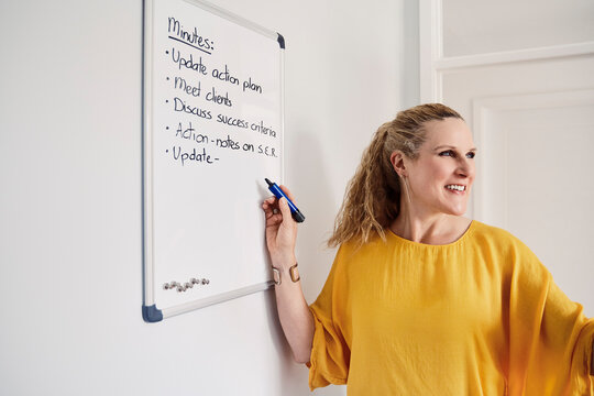 Smiling businesswoman writes ideas on a whiteboard in her home office