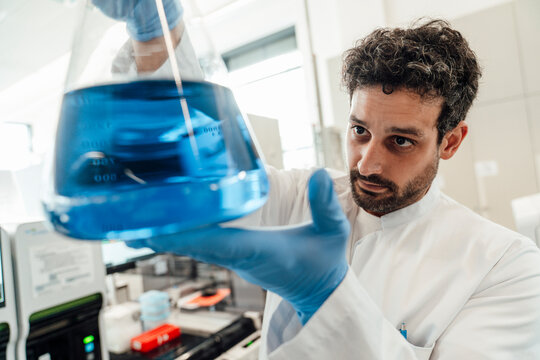 Scientist examining blue liquid in laboratory flask