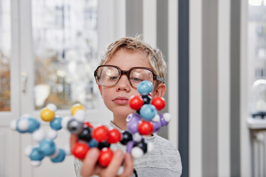 Boy wearing oversized glasses looking at molecular model