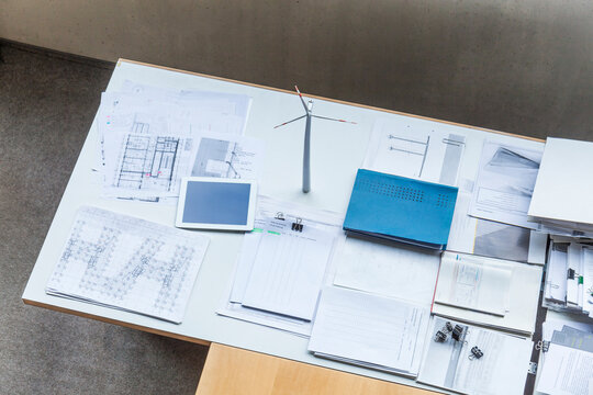 Wind turbine model, construction plans and tablet on table in office