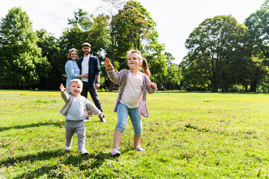 Happy family playing with soap bubble in a park