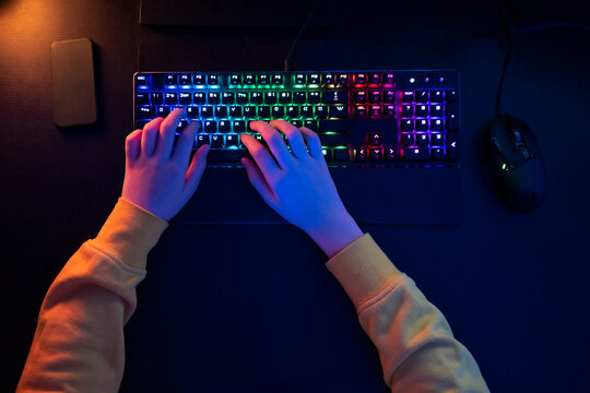 Boy typing on multi colored keyboard at table