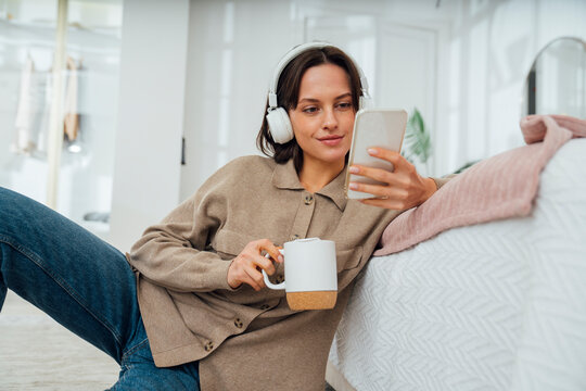 Smiling young woman with coffee cup using mobile phone