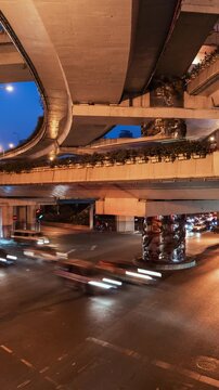 Asia, China, Shanghai, day to night cityscape vertical time lapse of road intersection in central Shanghai, busy with rush hour traffic and commuters