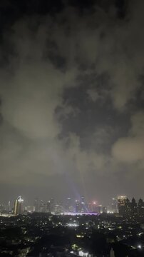 Jakarta skyline at night beneath dramatic clouds with glowing Senayan Stadium lights, ideal for city branding, travel, business, news, and urban lifestyle projects.