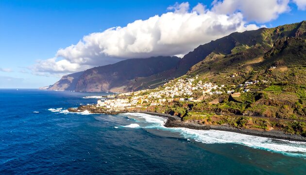 Aerial view of a coastal town nestled along a rocky shore, shadowed by lush, imposing mountains under a bright sky