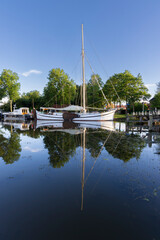 Fototapeta premium Sailboat moored on a calm canal with perfect reflection in Dokkum Friesland Netherlands town harbor