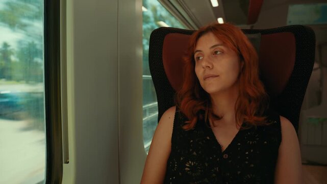 A red hair woman travels happily on a high speed train in Italy