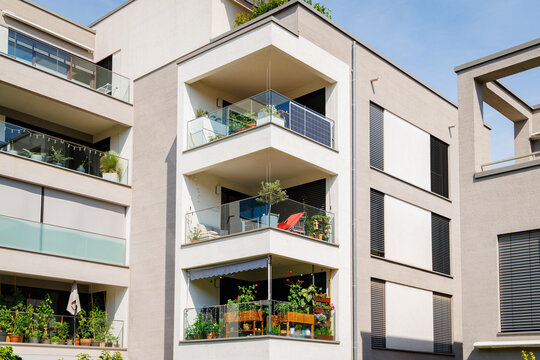 People gardening on balconies of an apartment building in a sunny area during springtime