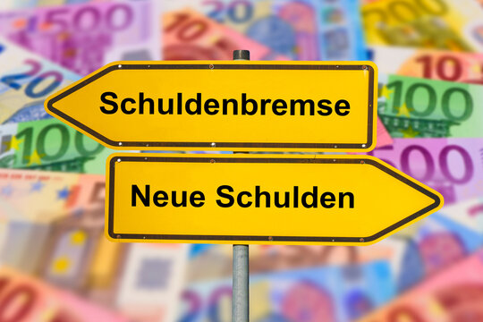 Zwei Wegweiser in gegens&auml;tzlicher Richtung sind beschriftet mit Schuldenbremse und Neue Schulden - FOTOMONTAGE - Symbolbild