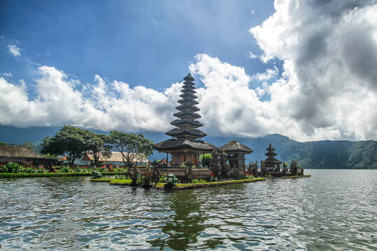 Bedugul, Bali, Indonesia - April 4, 2018: Pura Ulun Danu Beratan, a famous Hindu water temple on Lake Beratan, with dramatic clouds and surrounding mountains in Bedugul, Bali, Indonesia.