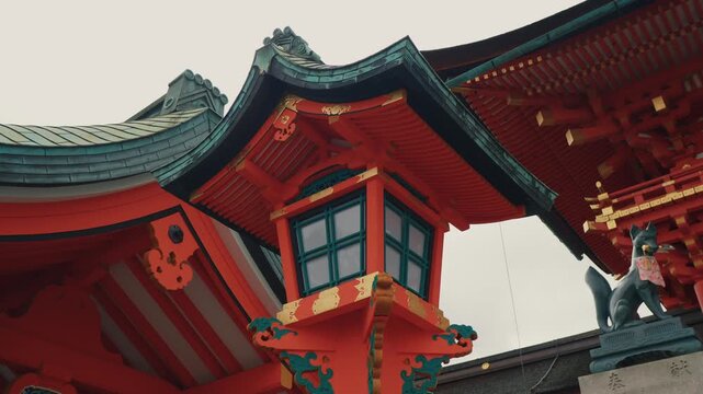 A richly decorated red pagoda tower features intricate golden ornaments and traditional curved rooflines in Japan.