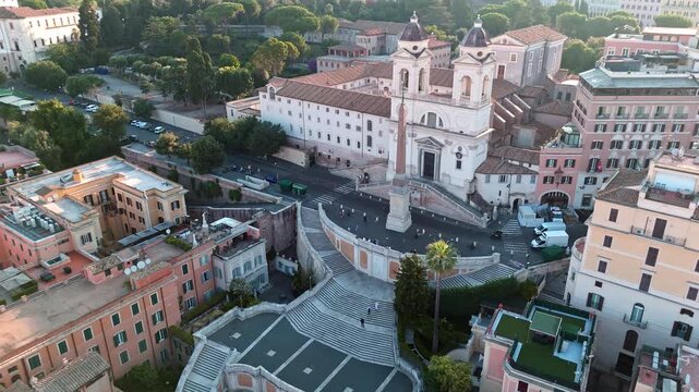 Spanish Steps rise toward Trinit&agrave; dei Monti church as a drone glides over surrounding Rome rooftops in soft evening light.