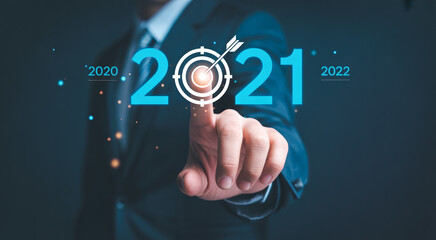 Fototapeta premium Businessman pointing to target with year 2021 in center, representing business goal and success.