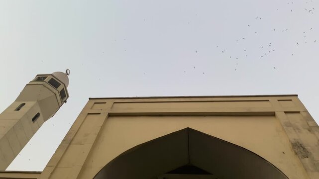 Birds flying over Baitul Mukarram National Mosque minaret at Dhaka, Bangladesh.