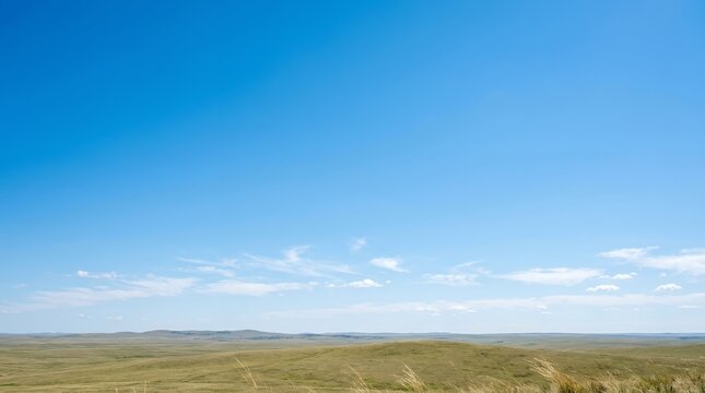 Vast open landscape under a clear blue sky with scattered clouds.