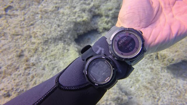 Scuba Diver Checking Wrist Compass and Dive Computer for Underwater Navigation over Sandy Seabed, POV Shot