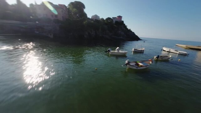 FPV drone glides over small harbor with boats, colorful buildings, and open sea view