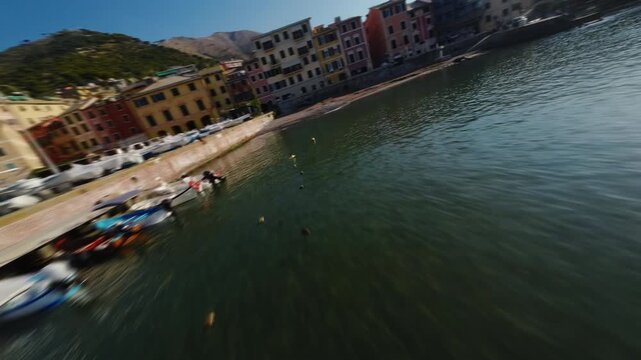 Dynamic FPV drone flight over small harbor with boats and colorful Mediterranean buildings