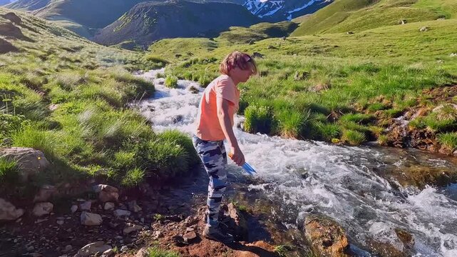Female camper washes tent stakes in a mountain stream in Georgia, cleaning outdoor equipment after campsite use for backpacking preparation, gear maintenance and responsible wilderness travel.