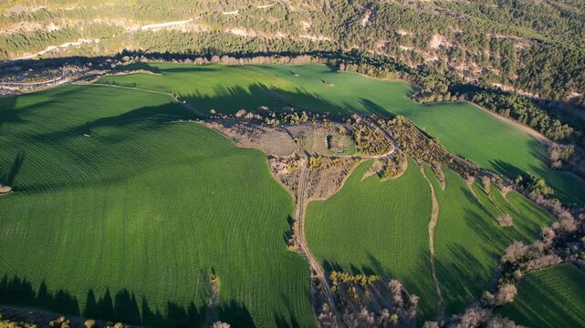 Backward reveal aerial footage of farmlands on sunny spring evening. Ceresola village, Huesca, Spain.