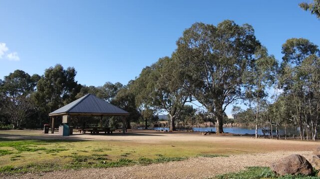 Picnic shelter beside a lake at Melton Botanic Garden, Victoria, Australia, surrounded by mature eucalyptus trees. Spacious parkland with Australian native vegetation and recreational public amenities