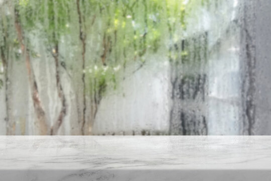 White Marble Table Top Counter with Blurred Natural Rainy Window Background for Product Display.