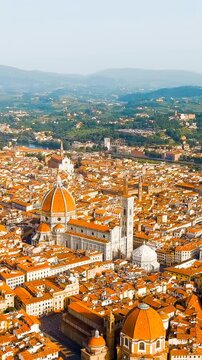 Vertical video. Florence, Italy. Cathedral Santa Maria del Fiore, its octagonal terracotta dome rising above the historic city center, aerial panoramic view over terracotta rooftops under clear summe