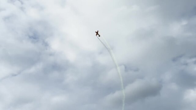 Close-up of stunt planes performing a vertical loop maneuver in a cloudy blue sky.