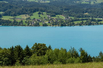 Fototapeta premium Turquoise alpine lake with lakeside village and forested hills