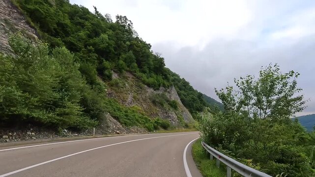 Mountain highway carries travelers beside Zhinvali Reservoir through forested Georgian terrain, supporting regional tourism, road trip planning and destination marketing across the Caucasus.