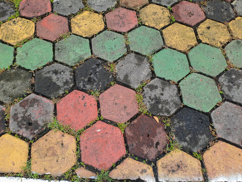 Textured red and green hexagonal stone pavers create a weathered pavement surface Abstract Background Concept Design