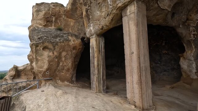 Rock-cut chambers open beneath carved sandstone ceilings at Uplistsikhe in Georgia, revealing columns, doorways, and ancient construction linked to archaeology, cultural preservation