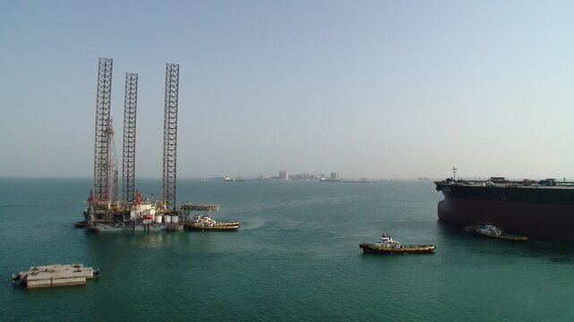 Oil drilling rig and cargo ship in calm blue ocean waters