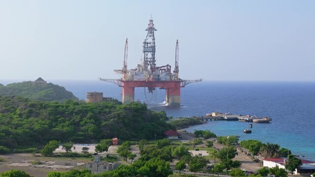 Offshore oil drilling rig in the ocean near coastal landscape