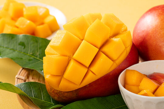 Fresh ripe cut mango fruit slices on yellow background.