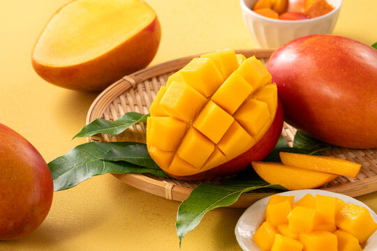 Fresh ripe cut mango fruit slices on yellow background.