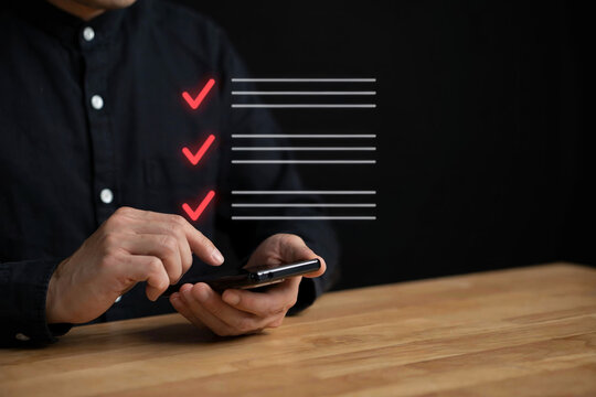 A person in a black shirt uses a smartphone, displaying a digital checklist with three red checkmarks on an invisible screen.