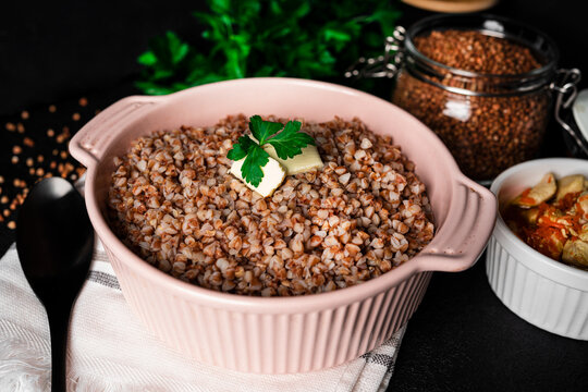 Buckwheat porridge in bowl on dark background. High quality photo