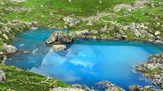 Blue Abudelauri Lake forms a turquoise focal point among rocky highland meadows in Georgia, offering destination imagery for adventure travel promotion, hiking itineraries, eco tourism